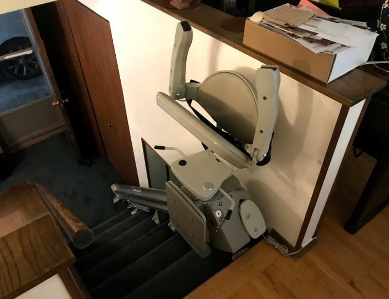 newly installed stairlift in Minnesota home with arms seat and footrest folded up at top landing