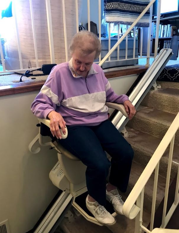 woman riding new Harmar SL600 stair lift in home in St. Paul