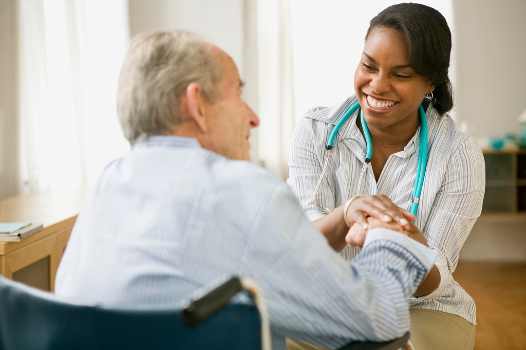 medical professional smiling at senior and holding his hand