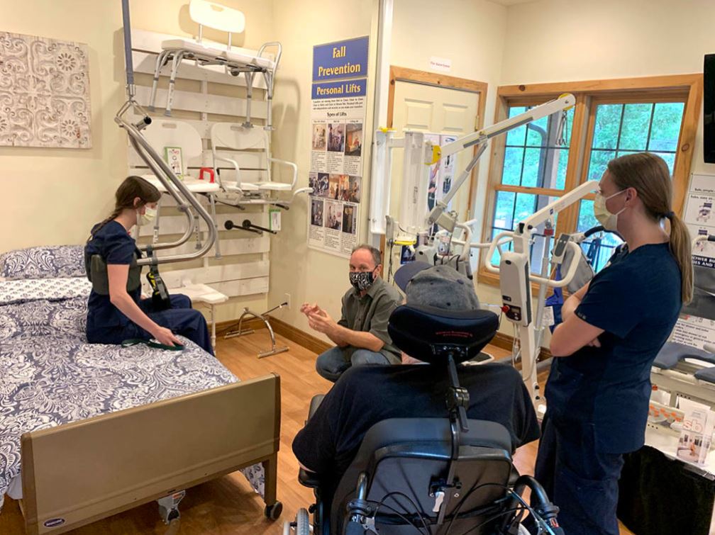 An OT demonstrates the use of a SureHands ceiling lift system to an elder disabled customer at Accessible System's show room in Denver