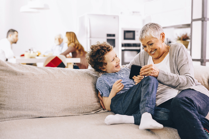 grandma sitting on couch with grandson with daughter and husband in background