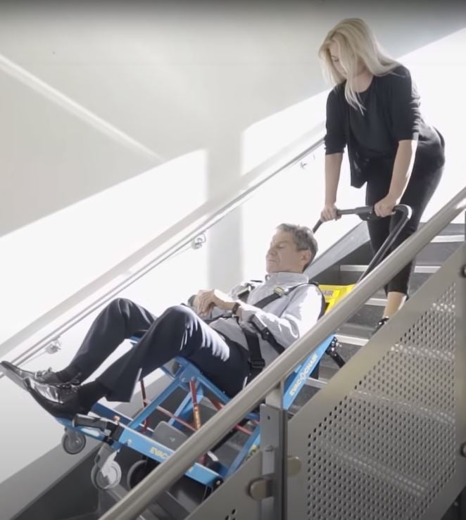 woman using stairclimber to help man with limited mobility safely get down stairs