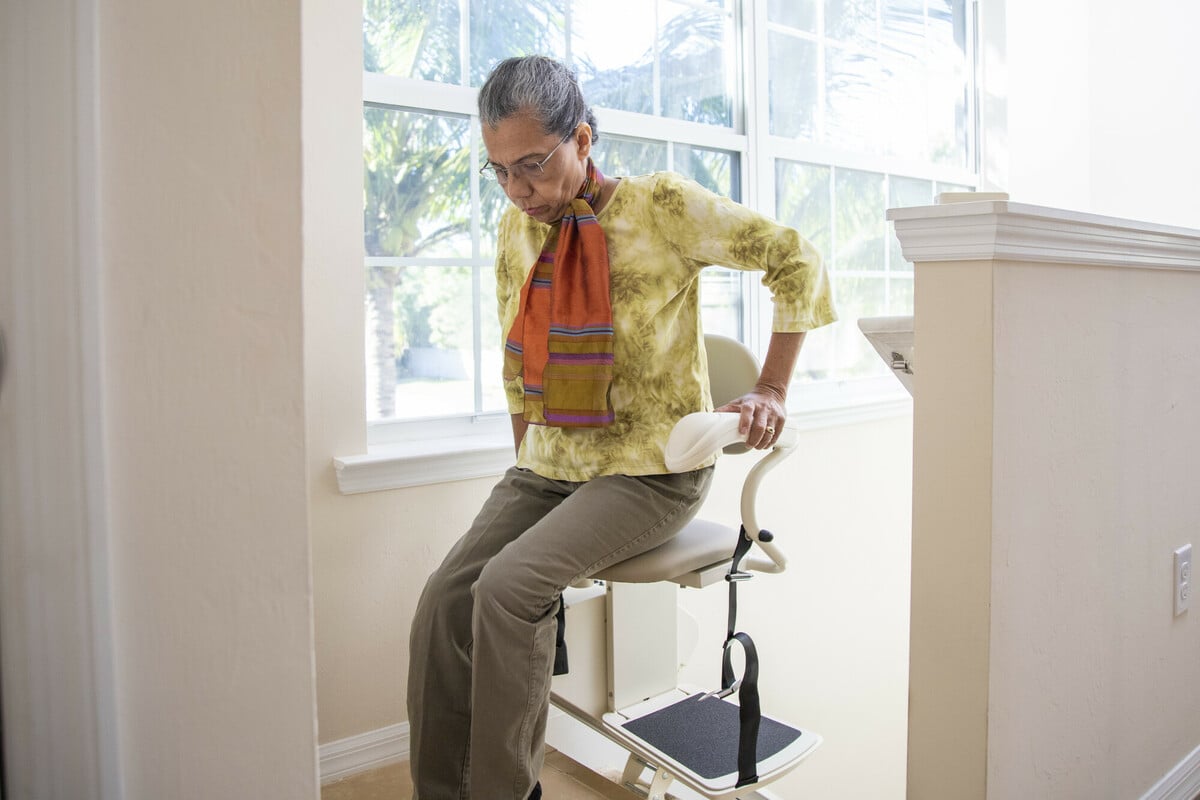 woman safely exiting stairlift at top of stairs using power swivel seat