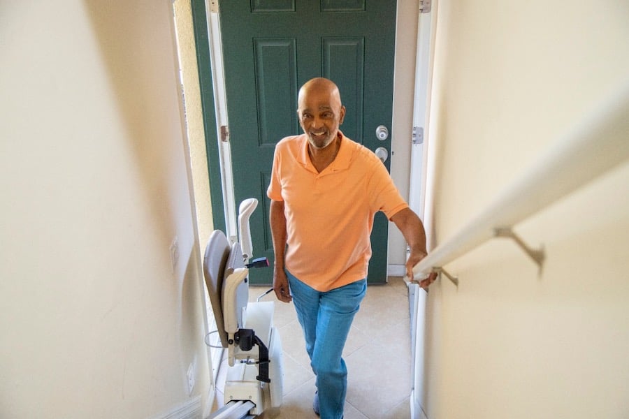 Man with Harmar SL600 stair lift from Lifeway Mobility, folded on stairs