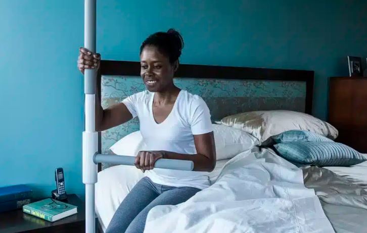 woman using super pole to safely get out of bed at home