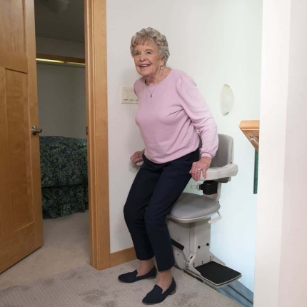 woman riding stair lift and smiling at grandchildren on stairs