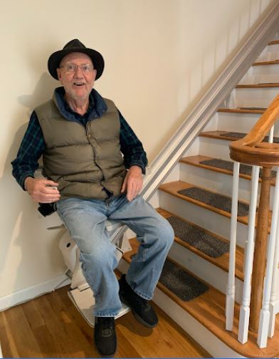 man riding his new stair lift that was installed by Lifeway Mobility