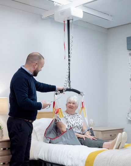 woman sitting up using ceiling lift installed by Lifeway Mobility