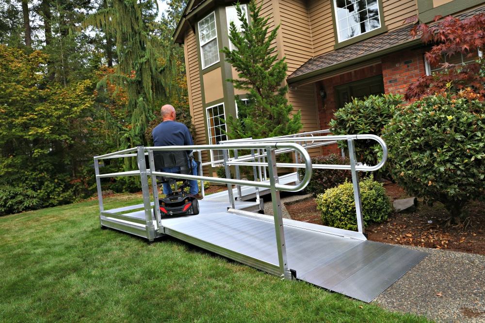 man riding scooter on newly installed wheelchair ramp in front of home