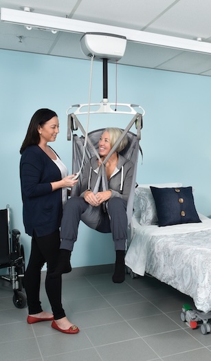 woman using fixed ceiling lift to safely transfer from wheelchair to her bed
