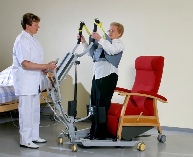 caregiver helps patient stand up using 1620 stand assist mobile patient lift