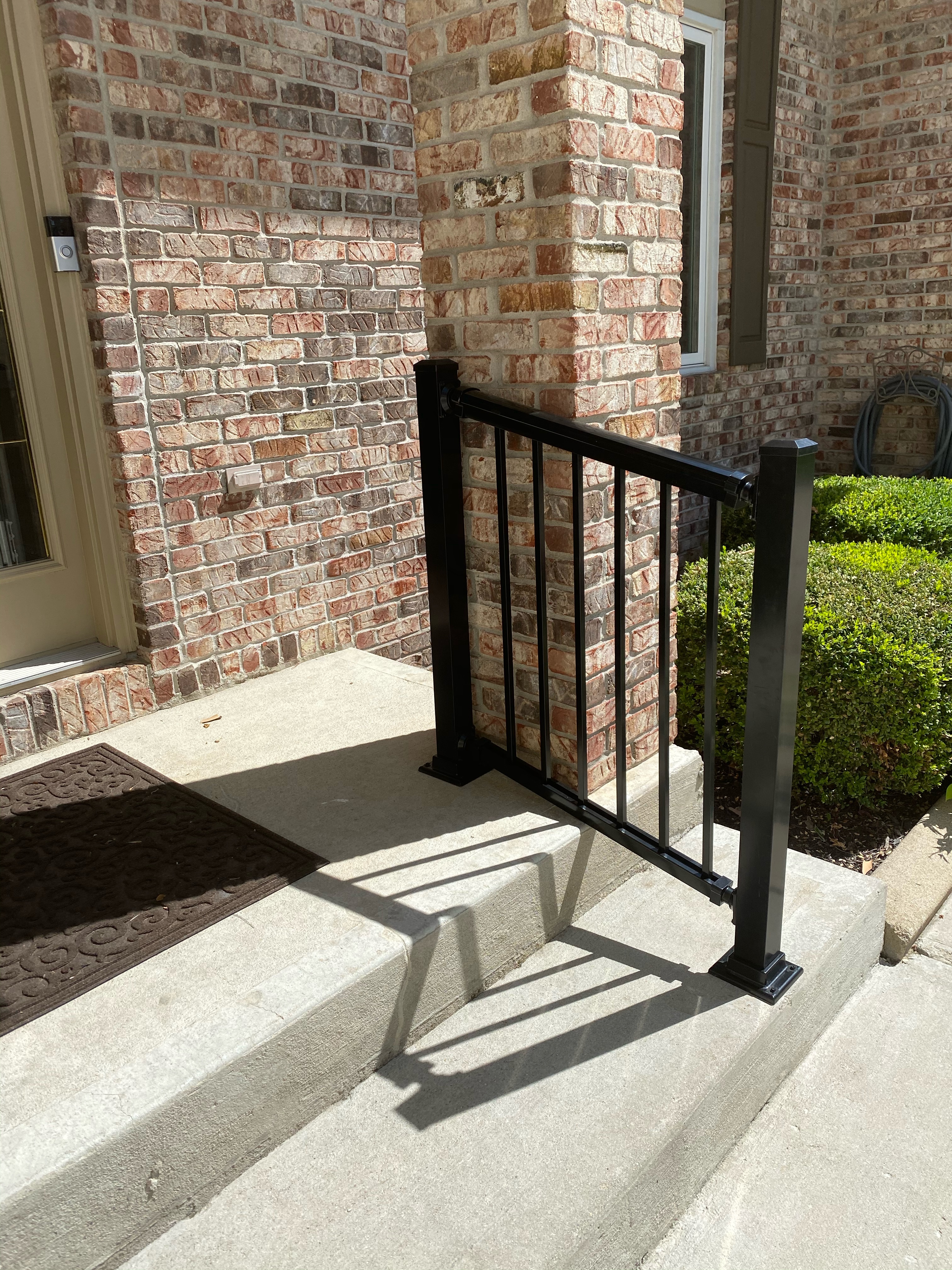 black aluminum handrail installed near front steps for additional support while navigating in and out of home