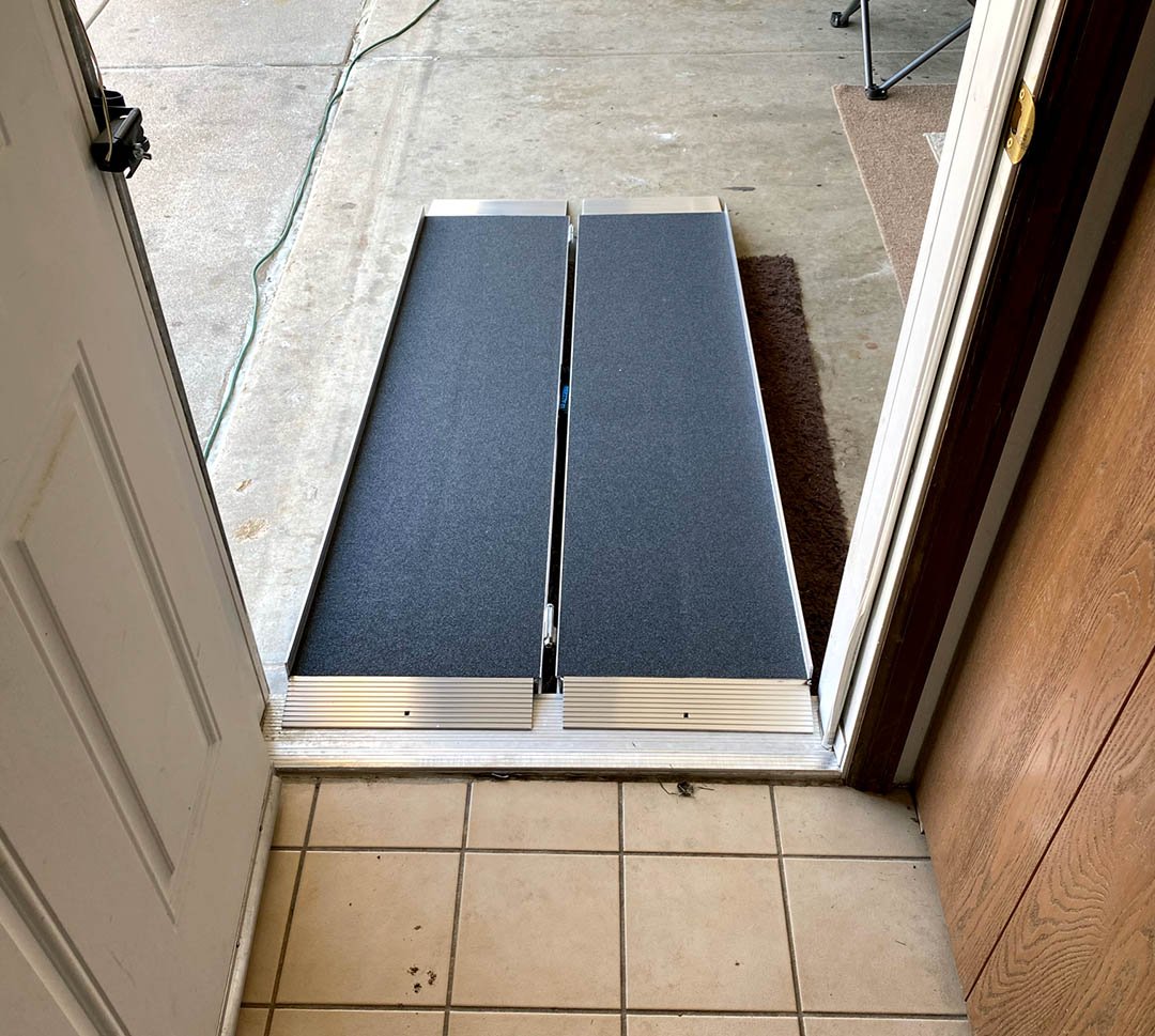 A foldable, suitcase style portable ramp installed at the doorway of this home makes mobility possible from the garage