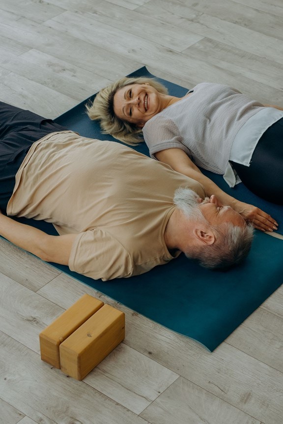 seniors laying down smiling at each other in yoga class