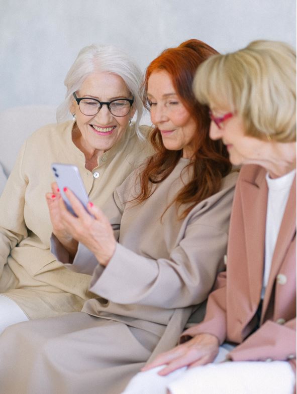 senior friends smiling together while looking at a smart phone