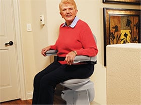 woman utilizing the arm-activated power swivel seat on a Bruno Elite stair lift