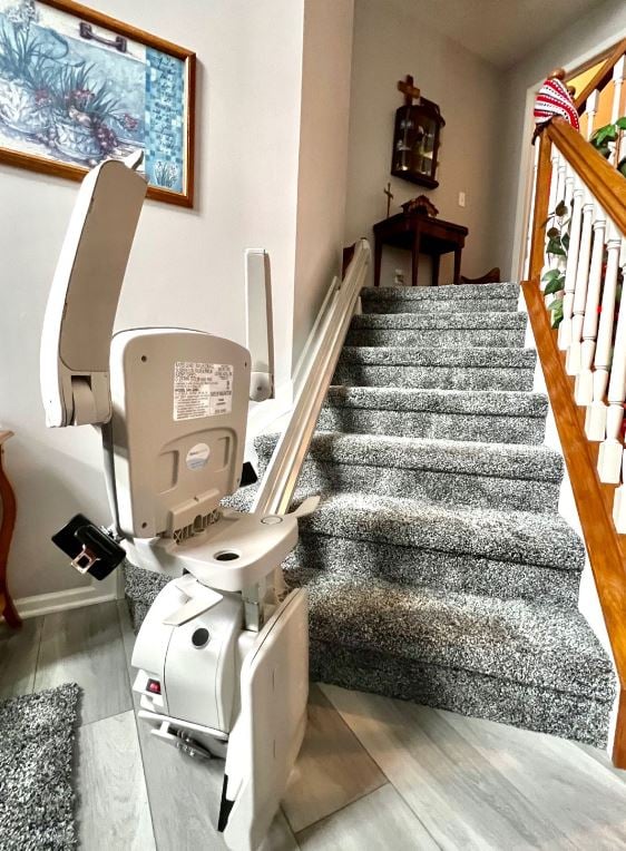 stair lift with chair components folded up at bottom landing installed by Lifeway Mobility
