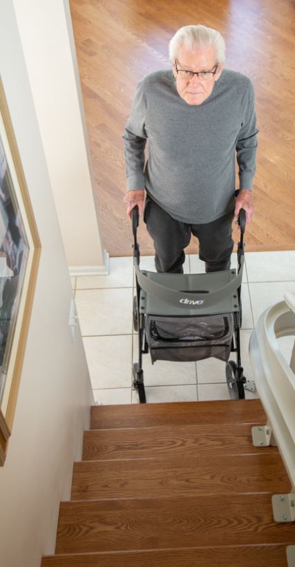 man with walker looking up at the staircase in his home