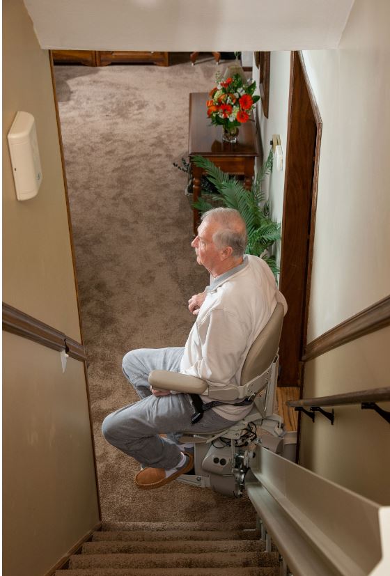 man riding stairlift at bottom landing on Christmas