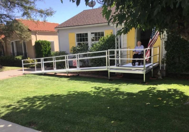 man-riding-scooter-up-wheelchair-ramp-to-enter-front-door-of-his-home-in-San-Diego