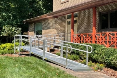 man-riding-scooter-up-wheelchair-ramp-to-enter-front-door-of-his-home-in-San-Diego