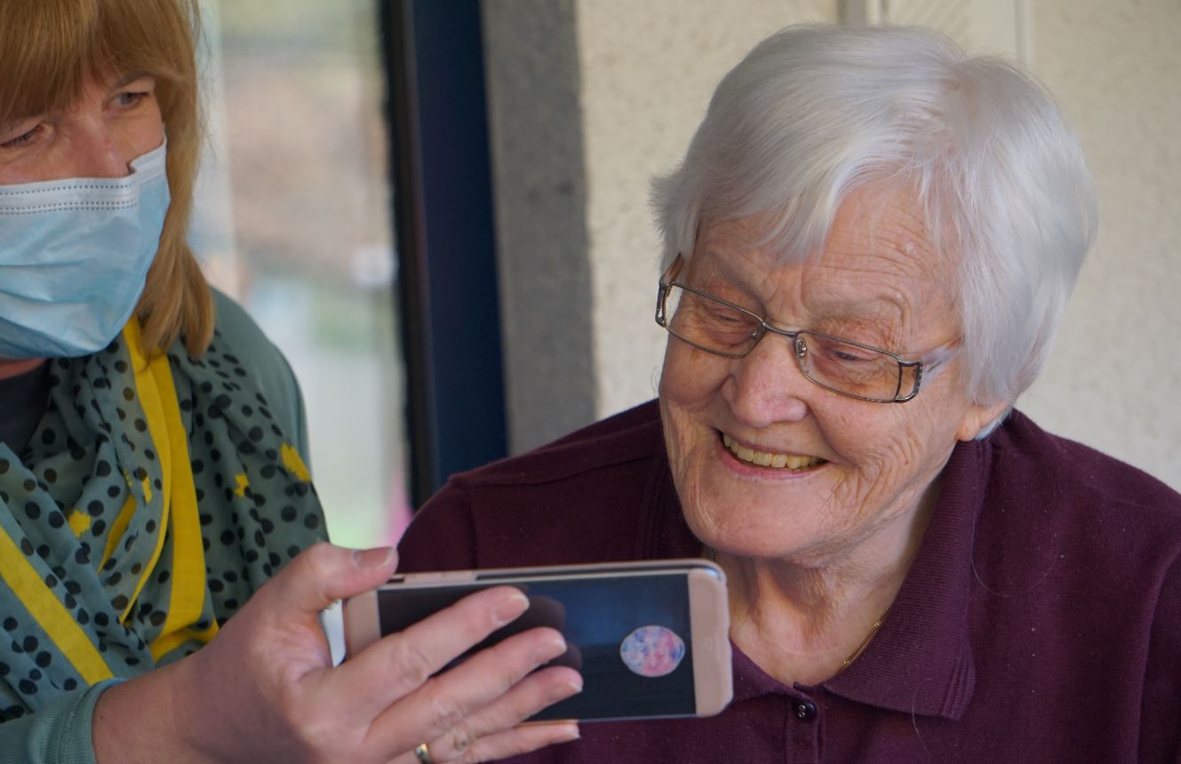 woman with mask showing senior woman info on her phone