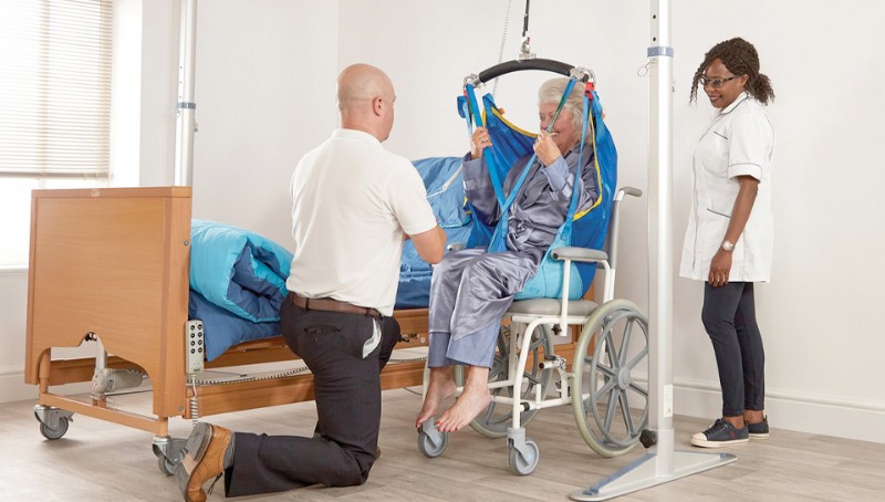 caregiver helps woman with sling for gantry patient lift