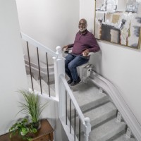 man riding Bruno elite curved stairlift installed by Lifeway Mobility