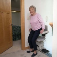 woman standing up from Bruno Elite stairlift at top landing of staircase