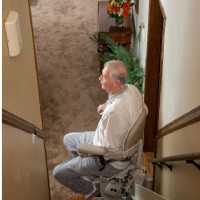 man riding stairlift at mid park position of staircase