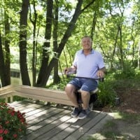 man sitting on Bruno outdoor curved stairlift at top landing