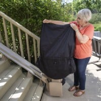 Woman puting outdoor protective cover on Bruno Elite stairlift