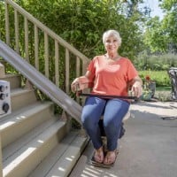 woman riding new outdoor Bruno Elite straight stairlift installed by Lifeway Mobility