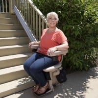 woman riding new outdoor Bruno straight stairlift installed by Lifeway Mobility