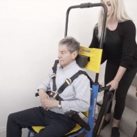 woman locking evac chair 800 to transport man up staircase