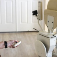 Lifeway Mobility customer using remote control to fold down components of Harmar Helix curved stairlift