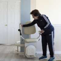 woman folds down components of Harmar Helix curved stairlift from Lifeway Mobility
