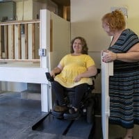 mom smiling at daughter in power chair using Harmar Highlander II VPL to safely exit garage