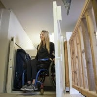 woman in wheelchair exits Harmar Highlander II VPL from Lifeway Mobility