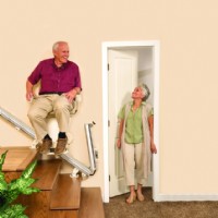 man riding Harmar SL600 with folding rail up as wife walks through door