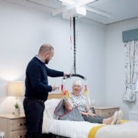 woman sitting in bed waiting to be transferred with a Lifeway Mobility ceiling lift