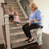 woman sitting on rental stair lift from Lifeway mobility at bottom of stairs during holiday season