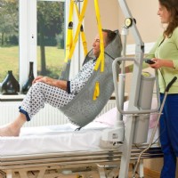 caregiver using mobile transfer lift 1630 to safely transfer man from his bed to bathroom