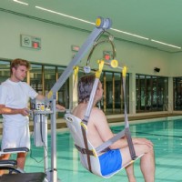 pool attendent helps man in wheelchair safely transfer into pool using Surehands pool lift from Lifeway Mobility