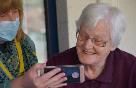 woman with mask showing mom her mobile phone