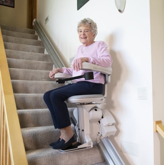 Woman riding a straight stair lift.