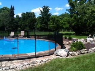 Well-lit pool fence with a stone walkway