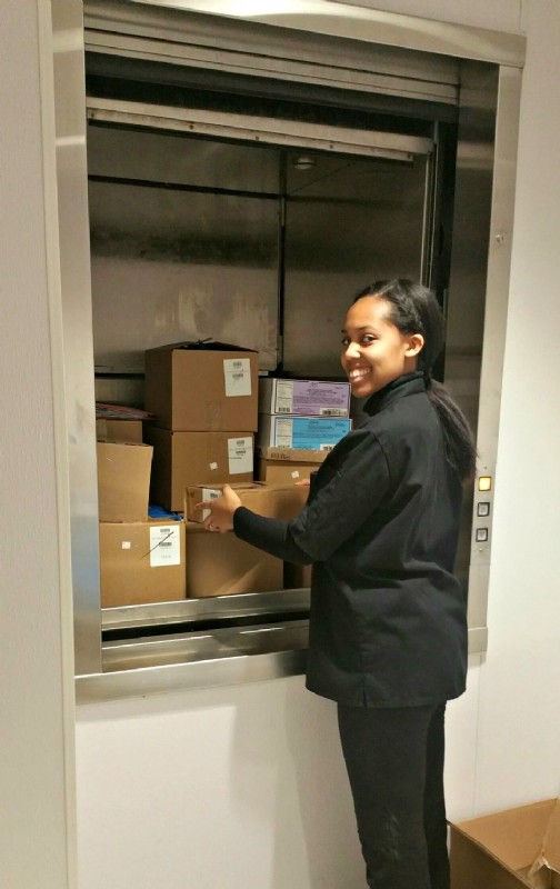 woman unloading boxes out of dumbwaiter in Fannie May candy store in Chicago