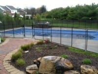 Protect A Child mesh pool fence with brick path