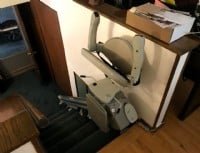 newly installed stairlift in Minnesota home with arms seat and footrest folded up at top landing